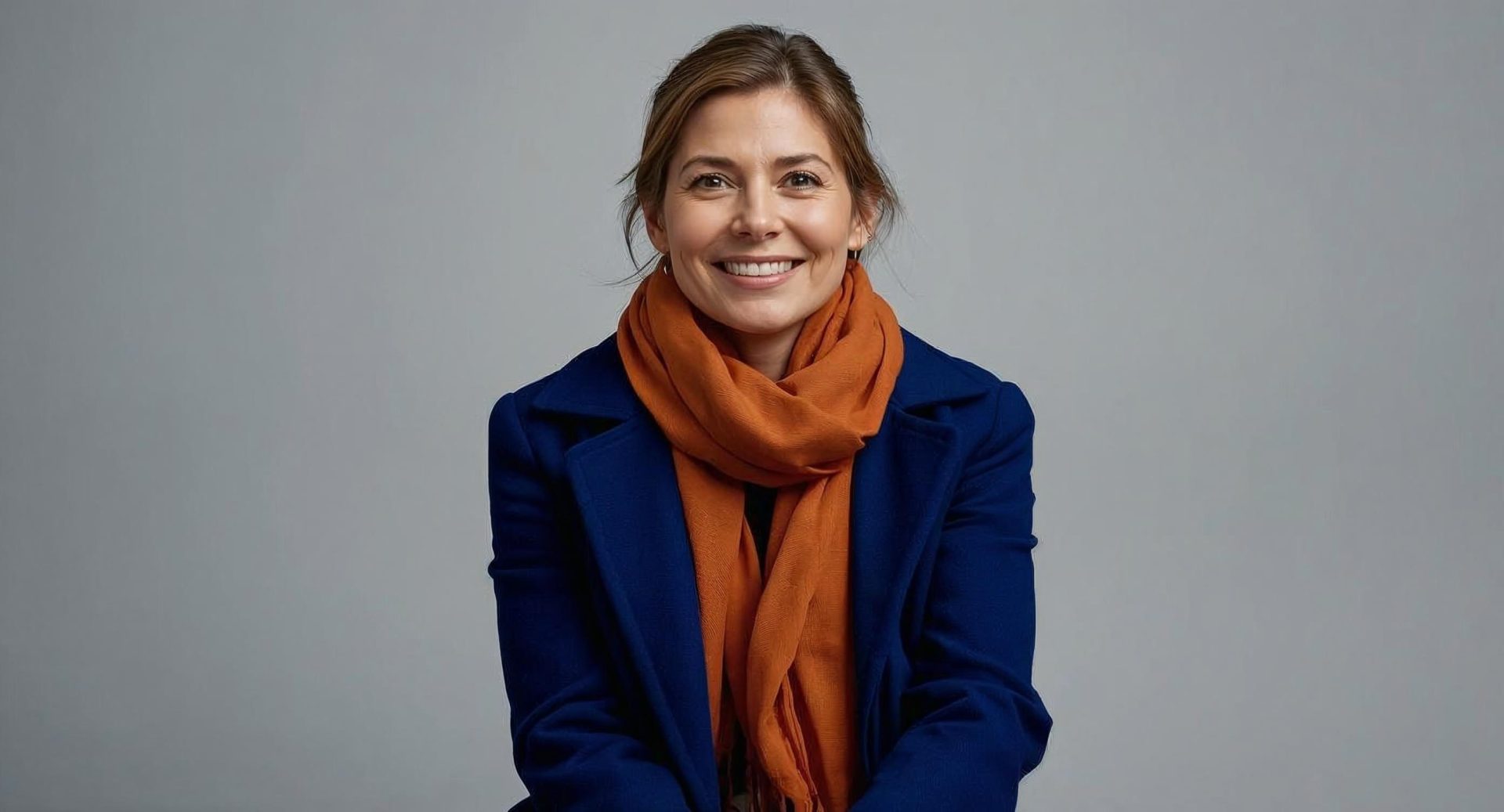 donna sorridente indossa cappotto blu e sciarpa arancione colori moda autunno inverno 2025 2026